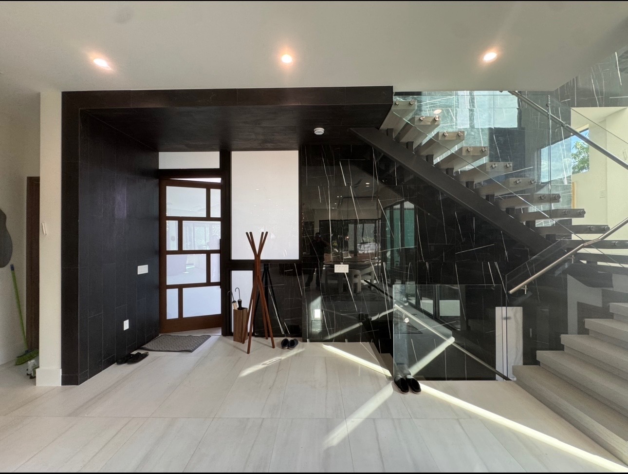 Finished foyer with dark accent wall and glass-rail staircase after construction was complete.