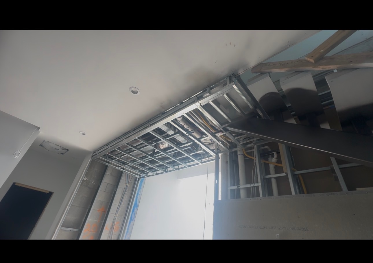 Newly framed interior soffit being built around overhead HVAC duct and plumbing routing.